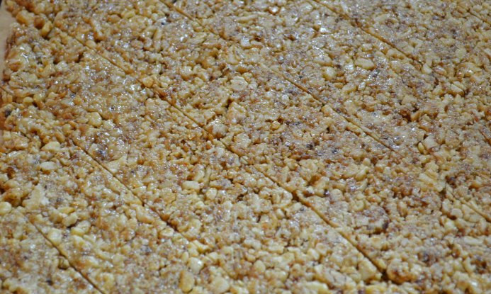 1. Этап. Козинаки из грецких орехов: Теперь смачиваем большую разделочную доску водой и выкладываем на нее полученную массу, быстренько раскатываем ее смоченной скалкой, пока мед не застыл. В итоге у нас должен получиться пласт шириной около 1 см.