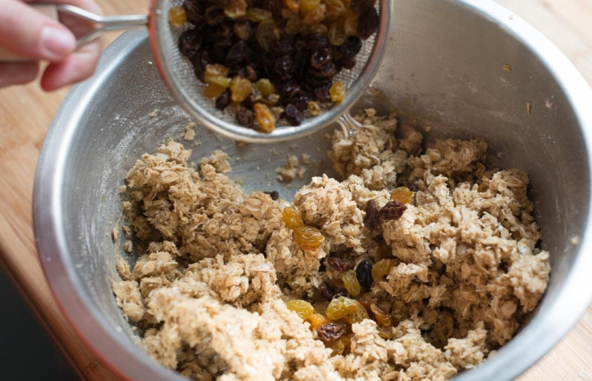 1. Этап. Печенье с геркулесом: С изюма слейте воду и просушите бумажным полотенцем. Отправьте его в тесто и вымешайте. Разогрейте духовку до 180 градусов.