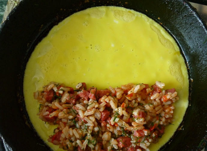 1. Этап. Омлет с рисом: Когда низ омлета загустеет, но верх будет еще немного жидким, выкладываем на одну половину омлета приготовленную начинку.