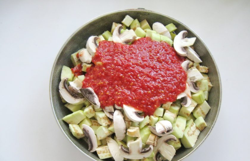 1. Этап. Икра из баклажанов с шампиньонами: Помидоры измельчите любым способом. Можно пропустить их через мясорубку, измельчить в блендере. Добавьте в сковороду. Посолите, добавьте сахар и налейте подсолнечное масло.