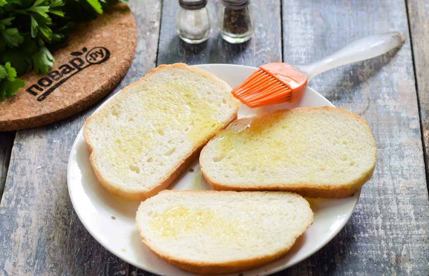 1. Этап. Брускетта в духовке: Ломтики батона смажьте ароматным маслом. Духовку прогрейте до 200 градусов. Переложите батон на противень и запекайте по 10 минут с каждой стороны. После посыпьте сухим чесноком, солью и перцем по вкусу.