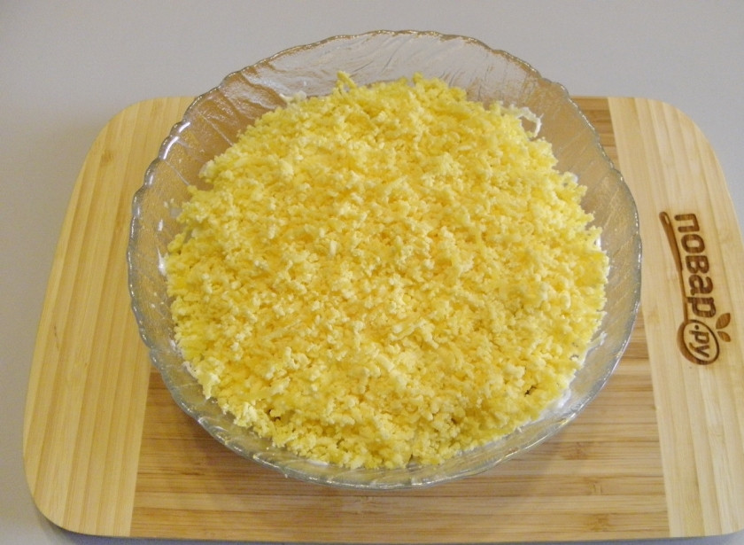 1. Этап. Салат Мимоза новогодний: Последний слой - тертые на мелкой терке яичные желтки. Теперь накройте салат пищевой пленкой и поместите его в холодильник на 1,5-2 часа.