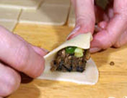 1. Этап. Кундюмы с грибами: 5. Половину столовой ложки начинки кладем на самую середину квадрата теста, водой смазываем края теста. Лепим треугольник, соединяем края, должен получиться пельмень.