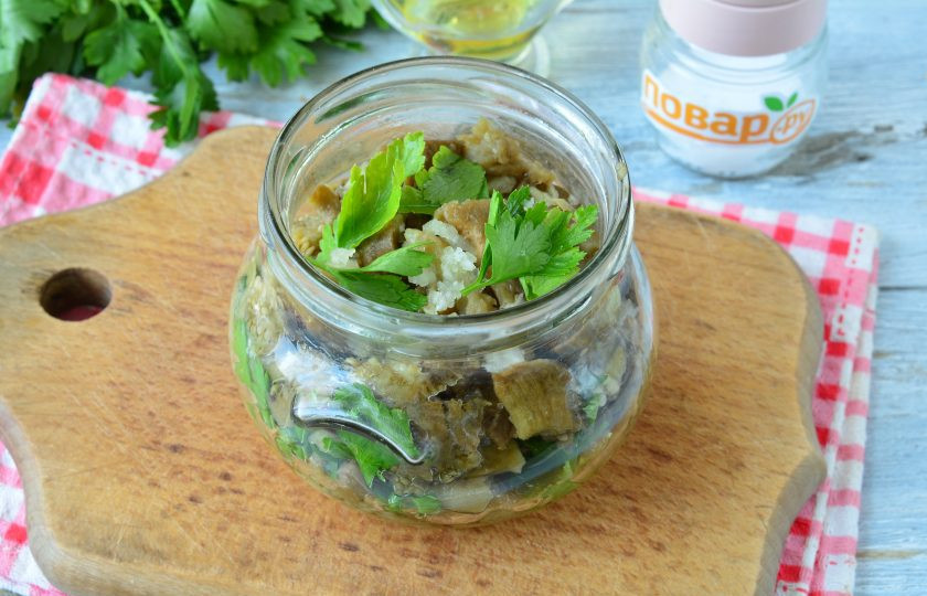 1. Этап. Баклажаны в духовке на зиму: Выкладывайте слоями баклажаны, чеснок и петрушку до верха баночки.