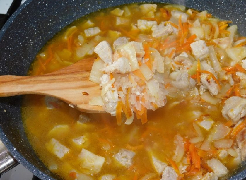 1. Этап. Мясная сковорода с рисом и кабачками: Затем добавьте промытый рис. Влейте воду и посолите немного. Перемешайте и доведите до кипения. Уменьшите огонь и накройте сковороду крышкой.