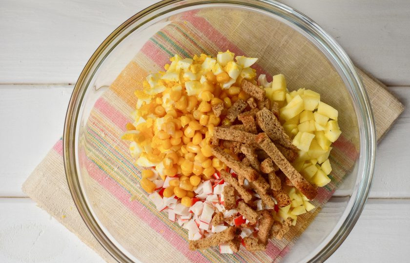 1. Этап. Салат Марсель с крабовыми палочками: Выложите кукурузу и сухарики.