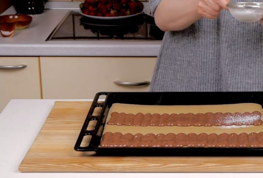 1. Этап. Торт-десерт Дары лета: 4. Заполните шаблоны на бумаге для выпечки, выдавливая тесто в форме полосок, посыпьте сахарной пудрой и оставьте на 15 минут. Оставшееся тесто распределите по дну формы. Отправьте в разогретую до 180 градусов духовку и выпекайте 12-15 минут.