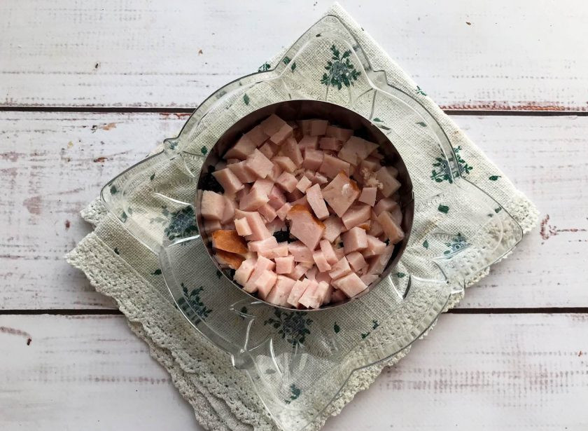 1. Этап. Салат с ветчиной и грецкими орехами: Ветчину мелко нарежьте, выложите поверх чернослива и смажьте майонезом.