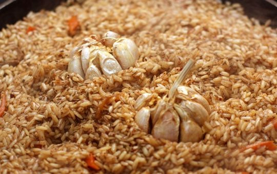 1. Этап. Плов на сковороде: Теперь выкладываем в середину риса головки чеснока и посыпаем его растертой зирой. Накрываем сковородку крышкой и уменьшаем огонь.