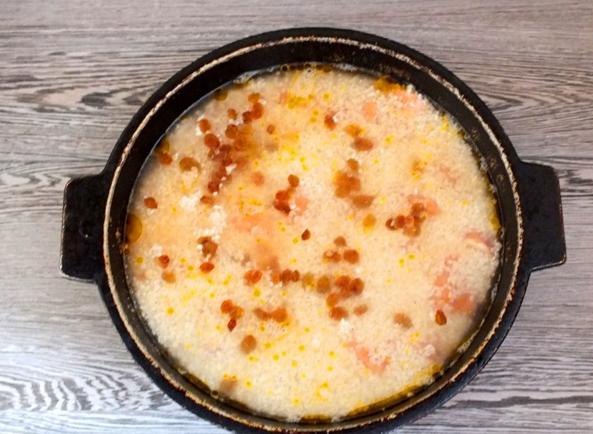 1. Этап. Плов из горбуши: Добавьте промытый изюм. Залейте водой так, что бы она была выше риса на 2 фаланги указательного пальца. Не перемешивайте! Поставьте на сильный огонь, доведите до кипения, после уменьшите до малого и варите до готовности. Через 20 минут, добавьте неочищенные зубчики чеснока. Закройте крышкой и продолжайте варить.