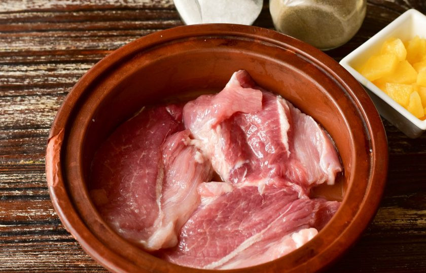 1. Этап. Свинина с ананасами и грибами в духовке: Форму для запекания смажьте растительным маслом, выложите в нее свинину, которую предварительно нарежьте так, как на отбивные.