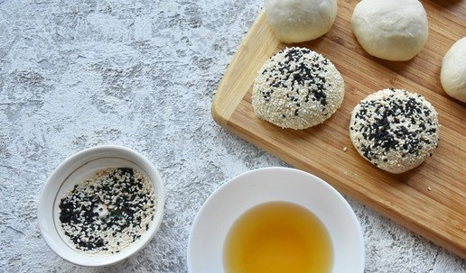 1. Этап. Пицца Большая перемена: В миску вливаю теплую воду и растворяю в ней мед. В другой миске соединяю белый и черный кунжут. Каждый шарик из теста окунаю сначала в медовую воду, а затем обваливаю в смеси кунжутного семени. Выкладываю заготовки на противень. Оставляю в теплом месте для подъема на 10 минут, накрыв кухонным полотенцем.