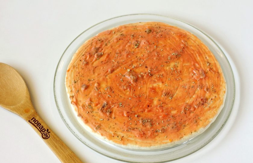 1. Этап. Пицца на готовой основе в микроволновке: Соедините майонез и кетчуп. Смажьте основу для пиццы готовым соусом. Сверху посыпьте прованские травы.