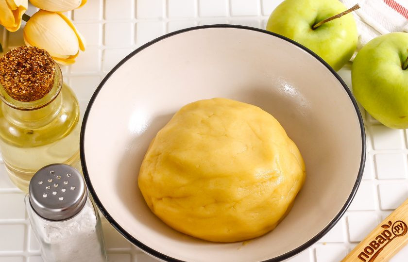 1. Этап. Песочный пирог с вареньем и яблоками: Сформируйте плотное песочное тесто и поместите его в холодильник на 20 минут, накрыв пищевой пленкой.