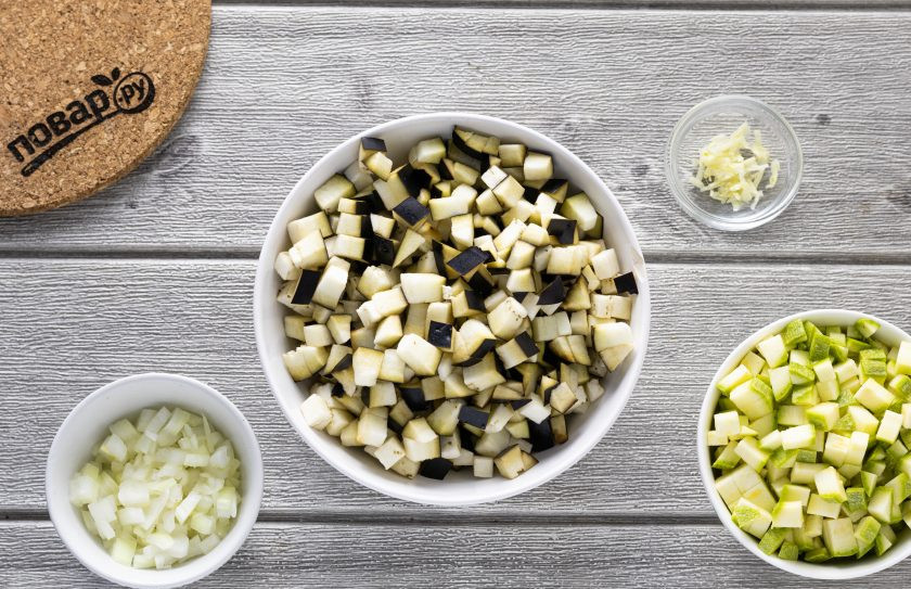 1. Этап. Овощная лазанья из кабачков и баклажанов: Нарежьте репчатый лук, кабачок и баклажан на мелкие кубики. Чеснок пропустите через пресс.