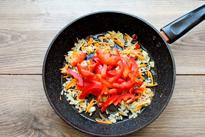 1. Этап. Кальмары по-азиатски: У болгарского перца удалите плодоножку и семена, порежьте соломкой. Добавьте перец в сковороду.