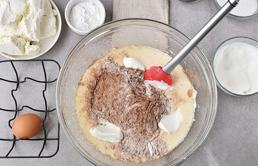 1. Этап. Шоколадный пирог с творогом: Всыпьте сухую смесь в миску с яично-масляной смесью, добавьте сметану, отложив 2 столовых ложки. Перемешайте легко.