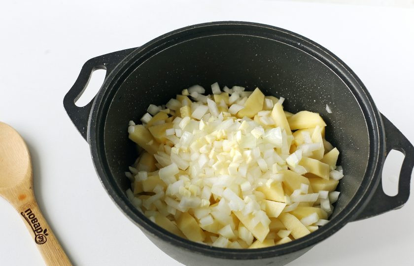 1. Этап. Картошка с грибами в казане: Выложите нарезанный кубиками лук и чеснок. Перемешайте и тушите под крышкой на среднем огне до готовности картофеля.