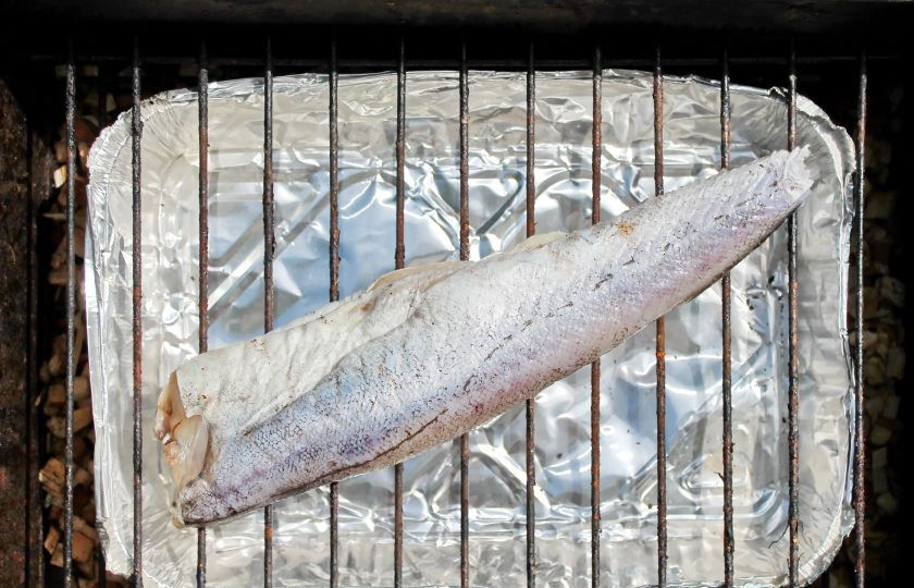 1. Этап. Минтай горячего копчения: Установите на щепу нижнюю решетку и положите противень для сбора жидкости. Поставьте верхний слой и выложите подготовленный минтай.