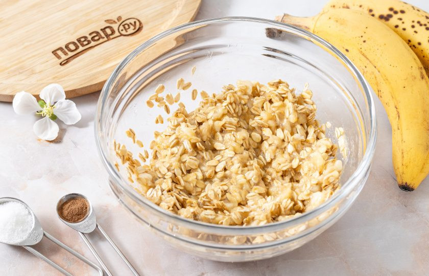 1. Этап. Протеиновое печенье без сахара: Начните постепенно добавлять овсяные хлопья частями и хорошо вымешивайте.