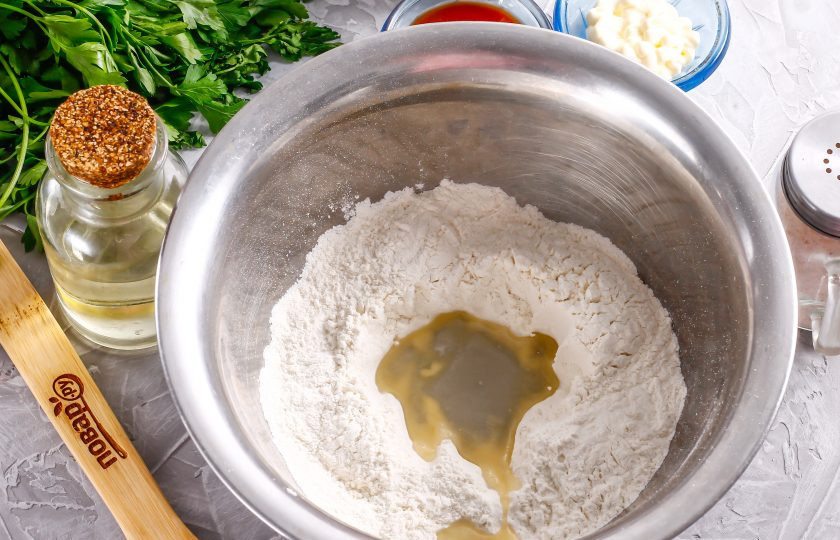 1. Этап. Пицца Мужская: Всыпьте в миску или глубокую тарелку пшеничную муку, сделайте в ней углубление. Всыпьте соль, влейте растительное масло и воду.