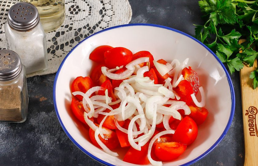 1. Этап. Теплый салат из кабачков и помидоров: Лук нарежьте тонкими полукольцами и добавьте к помидорам.