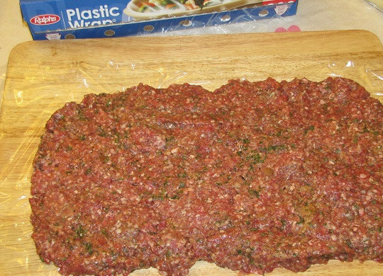 1. Этап. Мясной рулет с сыром: 3. Разделочную доску или рабочую поверхность застелить пищевой пленкой. Выложить фарш, разровнять и сформировать прямоугольник. Такой же мясной рулет с сыром в домашних условиях можно сделать и из тонко нарезанный ломтиков мяса, однако в данном варианте он будет нежнее.