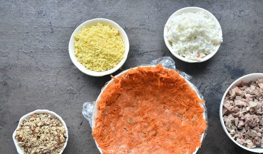 1. Этап. Салат Приручить дракона 2024: Для приготовления салата готовы все компоненты. Круглое блюдо прокладываю пищевой пленкой. Салат выкладываю слоями. Первый слой половина моркови с изюмом. Перед тем как выложить слой, добавляю в начинку сырный соус и перемешиваю.