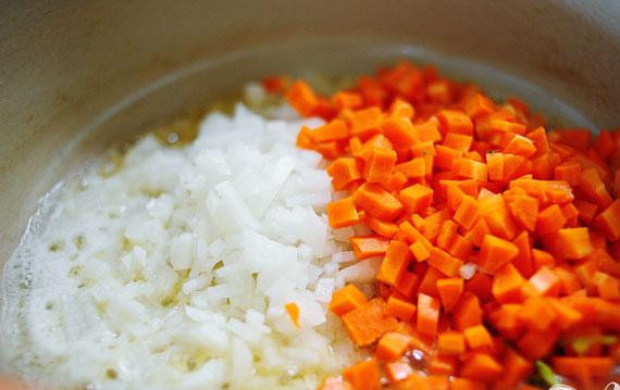 1. Этап. Весеннее ризотто: Мелко нарезать лук, сквош и зеленый лук. Нарезать морковь кубиками. Налить куриный бульон в маленькую кастрюльку. Довести до кипения. В большой сковороде нагреть 2 ст. ложки оливкового масла и 2 столовые ложки сливочного масла. Добавить нарезанные лук и морковь. Перемешать и жарить 1-2 минуты.