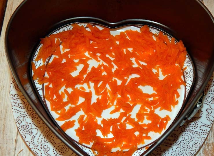 1. Этап. Салат с киви и ветчиной: На круглое блюдо положите форму в виде сердца, обычно её используют для выпечки, только дно снимите. Морковь натрите на крупной тёрке и выложите на дно тарелки первым слоем.
