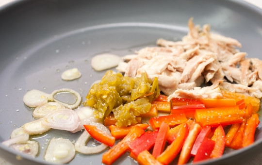 1. Этап. Мексиканский бурито: Порежьте мелко оба вида перца, лук, курицу разберите на волокна. На сковороде разогрейте масло и обжарьте эти продукты.