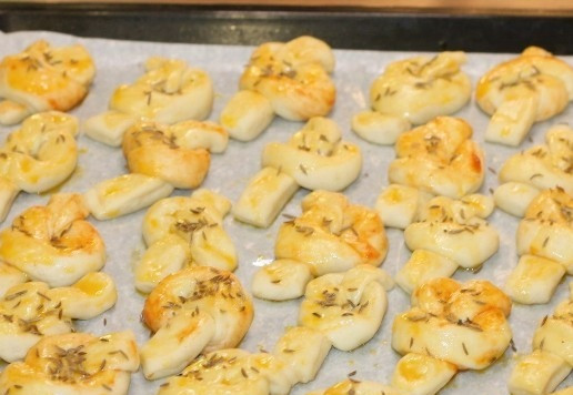 1. Этап. Морские узелки с чесночным маслом: 11. Противень застелите пекарской бумагой, смажьте сливочным маслом и выложите заготовки. Накройте противень пленкой и оставьте в теплом месте на 30 минут. Затем можно смазать узелки взбитым яйцом и посыпать тмином.