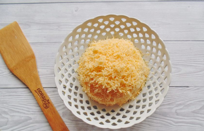 1. Этап. Салат Яблоки на снегу: Сыр натрите на мелкой тёрке и выложите поверх яиц, окончательно формируя салат.