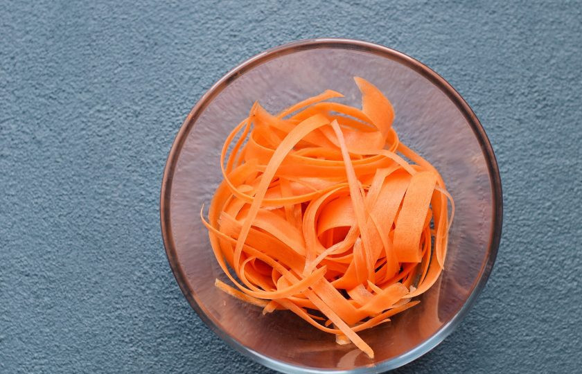 1. Этап. Спагетти из моркови: Морковь очистите от кожуры, затем с помощью овощечистки нарежьте на тонкие полосы.