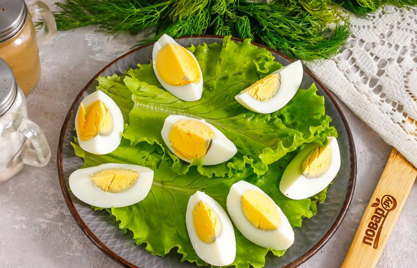 1. Этап. Салат с креветками и соевым соусом: Промойте листья салата, стряхните с них лишнюю жидкость и выложите на тарелку. Очистите куриные яйца от скорлупы и промойте, нарежьте четвертинками и выложите на листья салата.