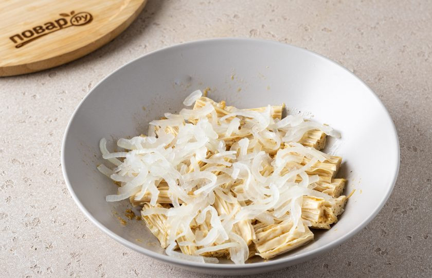 1. Этап. Салат из соевой спаржи с огурцом: Репчатый лук нарежьте тонкими полукольцами, залейте кипятком и оставьте на 1-2 минуты. Затем промойте лук в холодной воде и тщательно отожмите. Переложите в миску со спаржей.