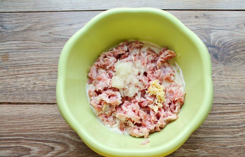 1. Этап. Ленивые пирожки с фаршем: Репчатый лук, чеснок почистите и натрите на мелкой терке, добавьте в миску с тестом и фаршем.