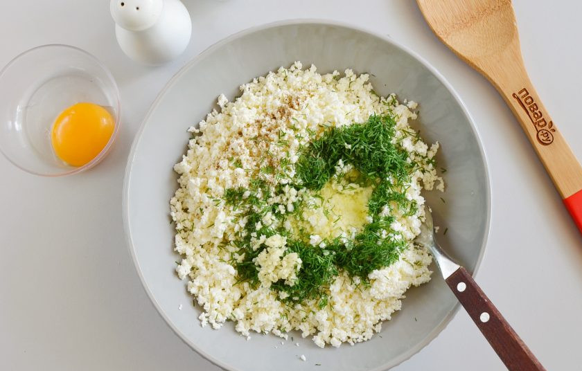 1. Этап. Слоеные конвертики с творогом: Приготовьте начинку. Творог разомните вилочкой, добавьте соль, перец, рубленый мелко чеснок и укроп, белок яйца. Желток отложите для смазывания конвертиков.