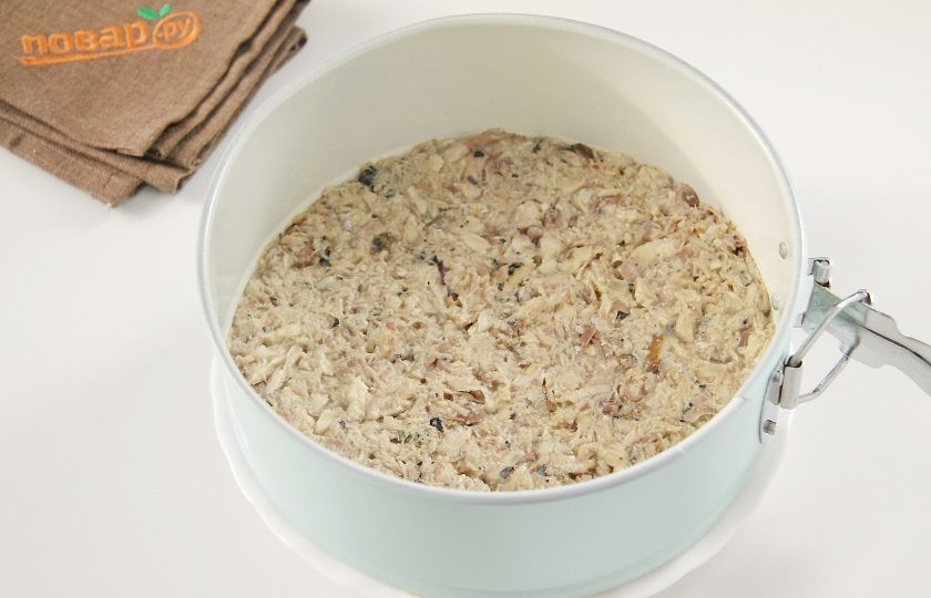 1. Этап. Мимоза на Новый год в виде свинки: На лук положите размятые консервы, смажьте слой майонезом и примните вилкой.