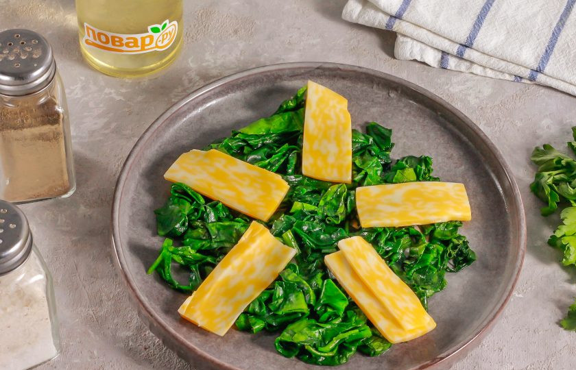 1. Этап. ПП салат с куриной печенью: Выложите шпинат на тарелку. Нарежьте твердый сыр ломтиками и добавьте к шпинату.