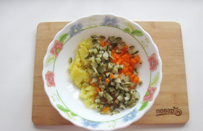 1. Этап. Оливье с курицей и яблоком: Маринованный или соленый огурец мелко нарежьте, выложите в салатник.