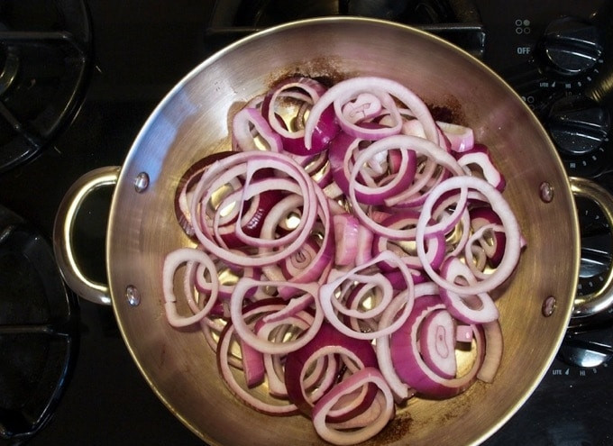 1. Этап. Говядина по-африкански: 4. После этого в жаропрочную сковороду или форму влейте оставшееся масло. Выложите красный лук кольцами.