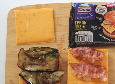 1. Этап. Брускетты с баклажанами и сыром: Обжарьте хлеб на оставшемся масле и выложите на хлеб по ломтику плавленого сыра гриль чиз от ТМ Hochland, обжаренный бекон, баклажан.
