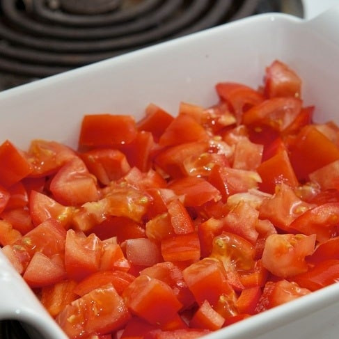 1. Этап. Яичница в духовке: Помидоры и перец, очищенный от семян, нарезаем на кубики и выкладываем в форму для запекания.