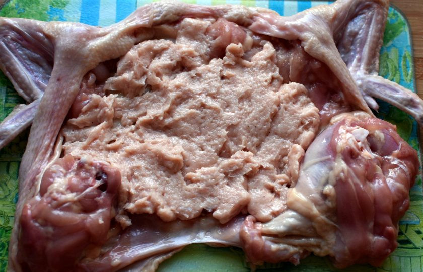 1. Этап. Курица по-царски, фаршированная блинами: Разложите куриную кожу с мясом на доске и смажьте внутреннюю поверхность не толстым слоем фарша.