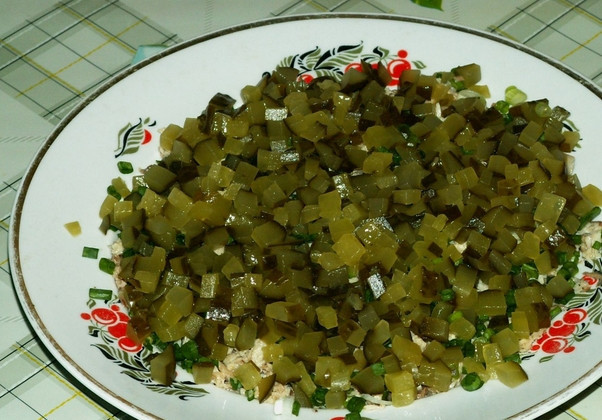 1. Этап. Салат с рыбными консервами: Измельчаем соленые огурцы. Выкладываем следующим слоем.