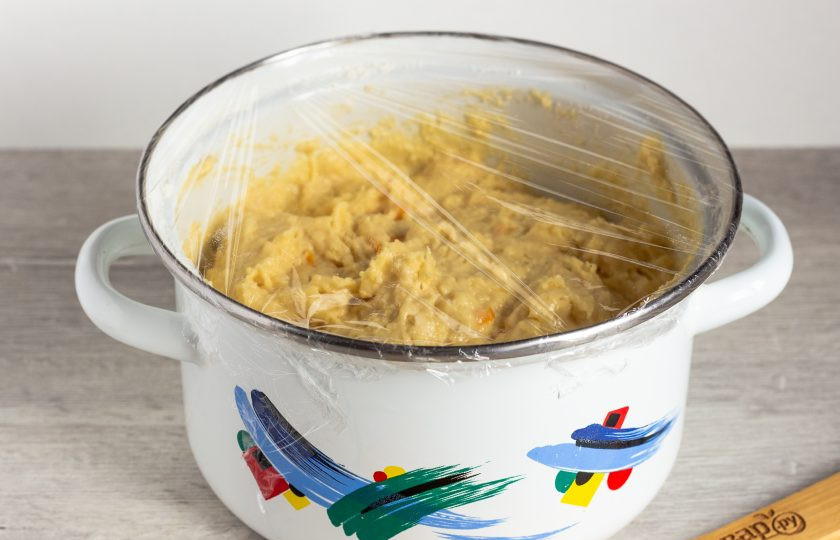 1. Этап. Простая пасха: Муку просейте. Постепенно добавляя в подготовленную массу, лопаткой замесите тесто. Оно будет как очень густая сметана. Накройте пищевой пленкой и уберите в теплое место на 40-45 минут.