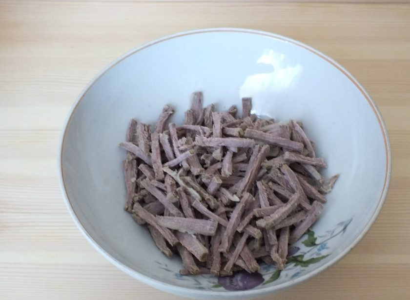 1. Этап. Салат Шахтерский с солеными огурцами: Отварную говядину нарежьте соломкой и положите в салатник.