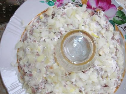 1. Этап. Салат Браслет: 4. Луковицу очистить и нарезать мелкими кубиками. Залить его кипятком на несколько минут, затем воду слить и лук просушить. Выложить сверху мяса.