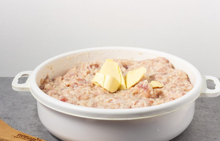 1. Этап. Куриная котлета по ГОСТу: Фарш тщательно разомните и перемешайте с замоченным хлебом, затем добавьте 30 грамм размягченного (не растопленного) сливочного масла. Посолите по вкусу и снова перемешайте.